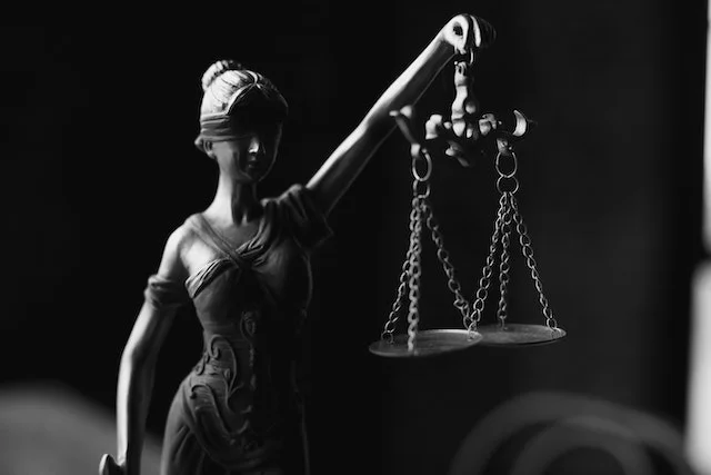 Black and white image of Lady Justice holding scales, symbolizing legal measures for charging late fees on invoices and enforcing payment terms.