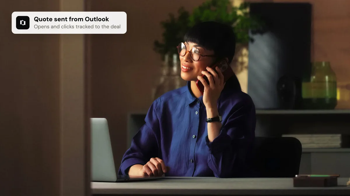 A salesperson on a call at their desk, with a Portant notification that the quote was sent from Outlook and is being tracked