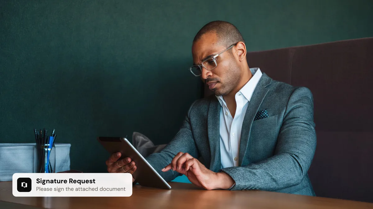 A reviewer reading a document on a tablet, with a Portant notification asking them to sign the attached document
