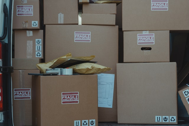 Stack of fragile-labeled shipping boxes with a visible packing list, illustrating the role of a proforma invoice in international shipping and customs documentation.